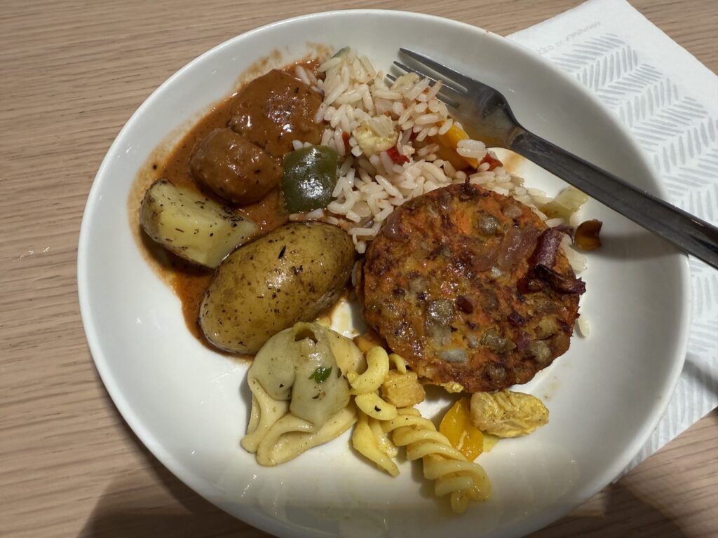 白い皿に盛り付けられたフィンエアーの機内食。ミートボール、ライス、ローストポテト、パスタ、野菜のパティがワンプレートになっている。