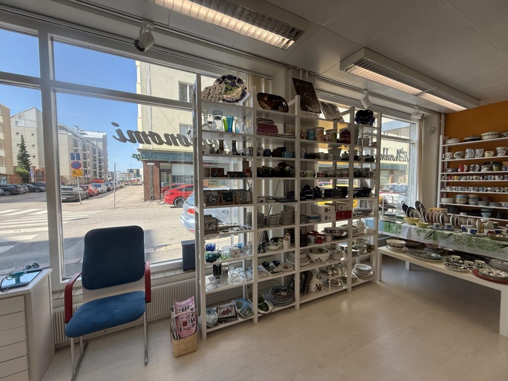日当たりの良いビンテージ食器店の店内。大きな窓際に置かれた白い棚に、色とりどりのカップや皿、グラスがびっしりと並んでいる。