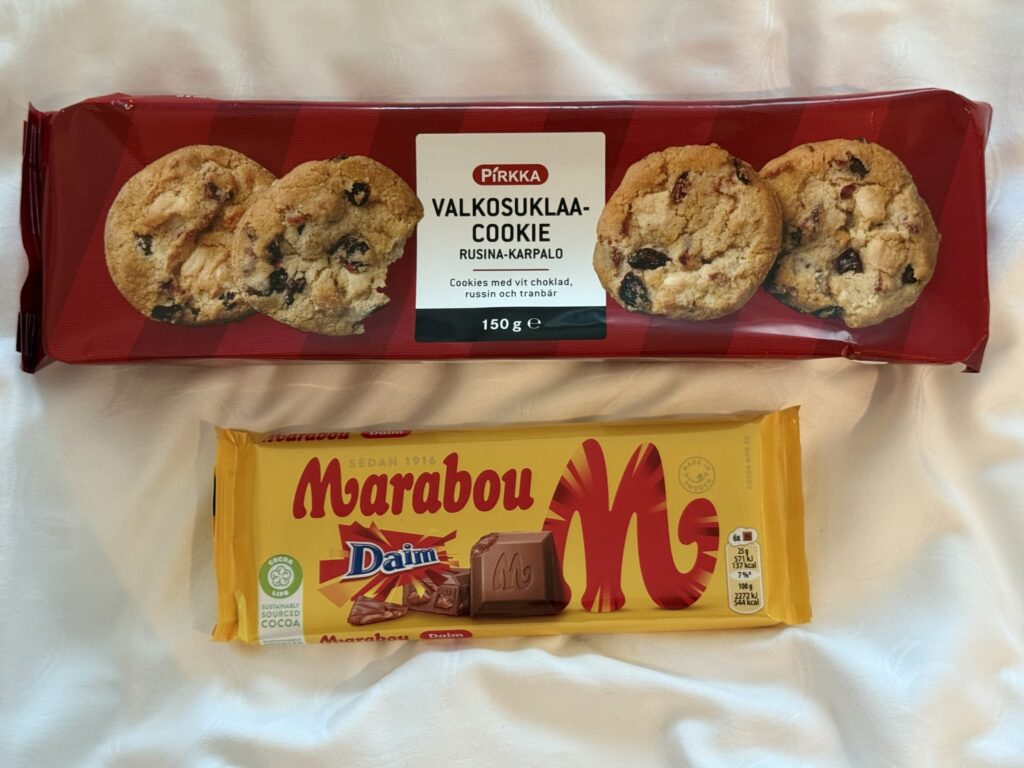 白い布の上に置かれた、Pirkkaの赤いパッケージのクッキーとMarabouの黄色いパッケージのチョコレートバー。