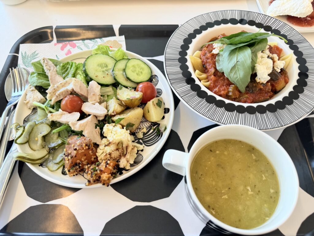ビュッフェで選んだ、チキンサラダ、トマトソースパスタ、スープが乗ったランチトレイ。
