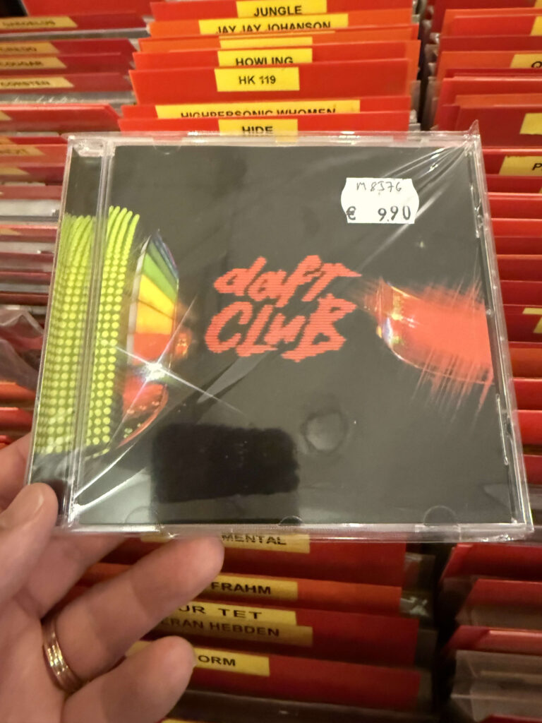 A hand holding a sealed CD of Daft Punk's album