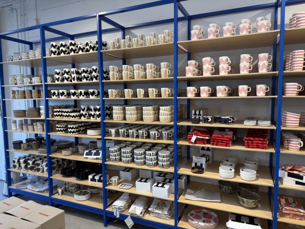 A view of tall, blue metal shelves packed with a wide variety of Marimekko mugs, bowls, and plates in numerous patterns.