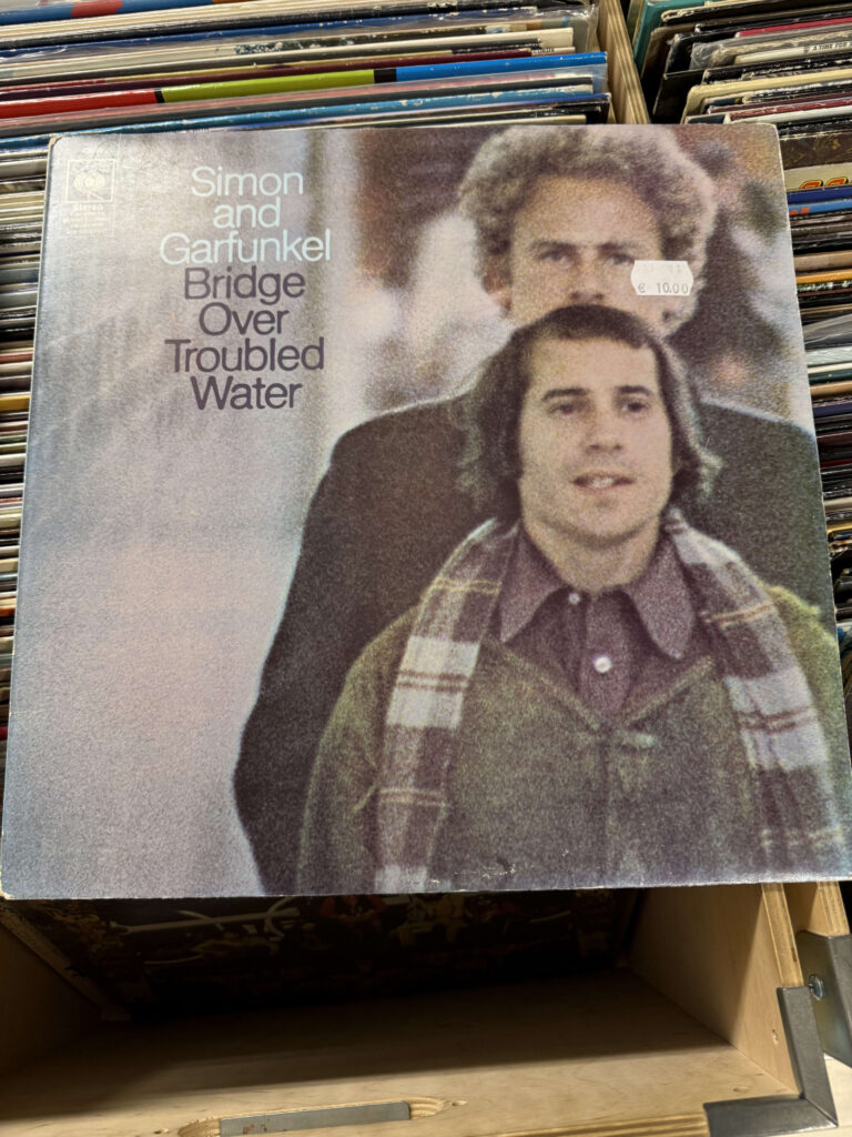 The vinyl record sleeve for Simon and Garfunkel's album 'Bridge Over Troubled Water' resting in a wooden crate filled with other records.
