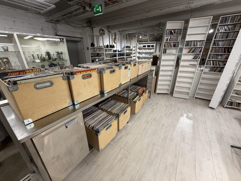 The interior of a secondhand shop in Helsinki, showing used records in wooden crates and CDs on shelves.