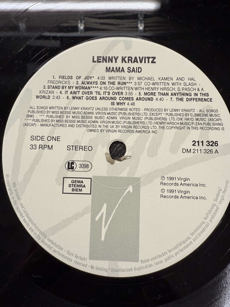 A close-up of the Virgin Records label on the vinyl record for Lenny Kravitz's album 'Mama Said,' showing the tracklist for Side One.