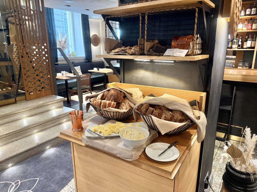 A stylish bread bar at a restaurant. A wooden counter displays several types of sliced bread in baskets, along with two kinds of butter.