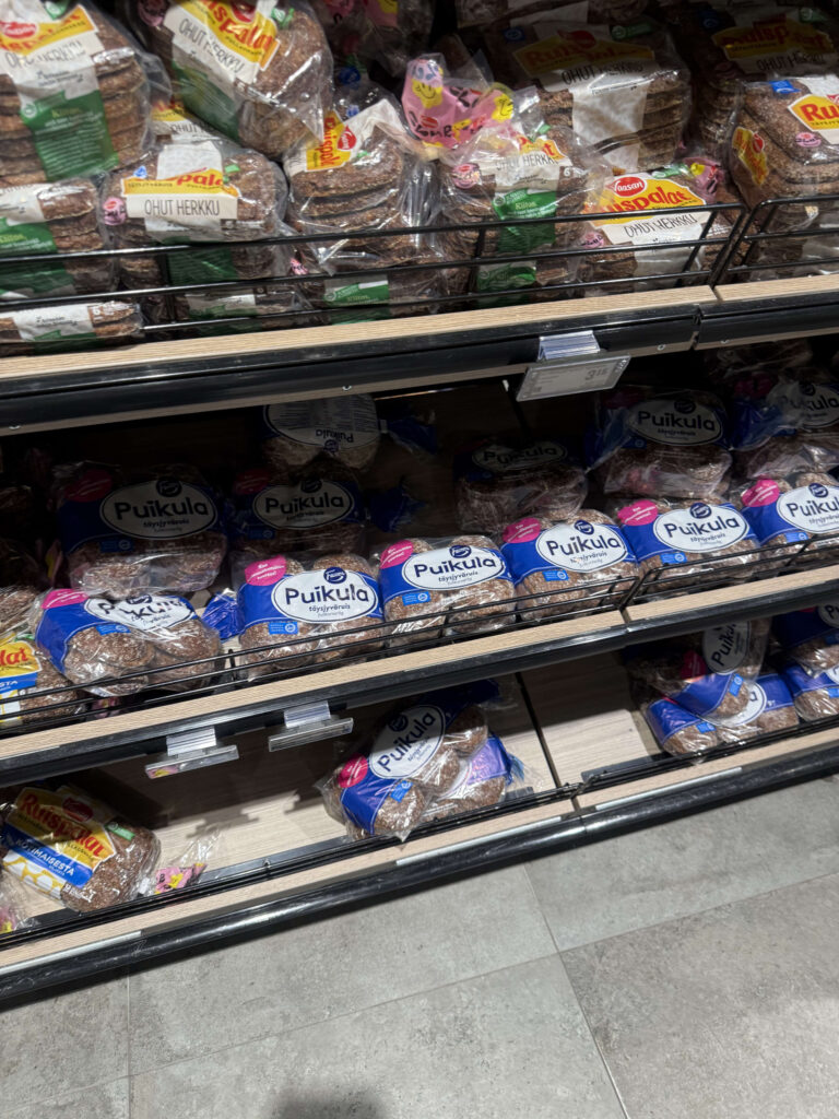 Various types of rye bread from the brand Fazer arranged on shelves at an airport shop.