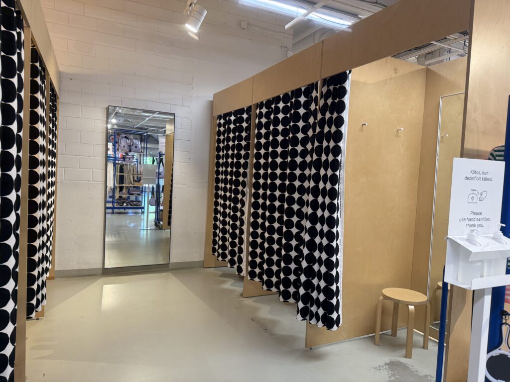 A fitting room area with light wood stalls and distinctive Marimekko black and white polka dot curtains.