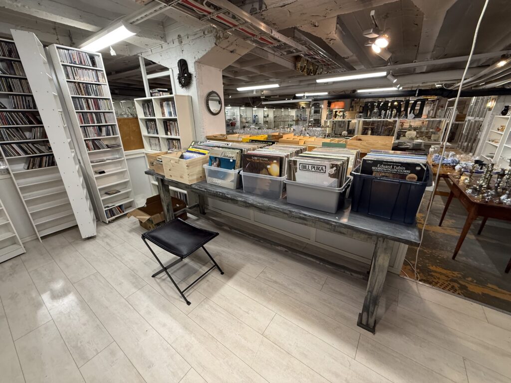 ヘルシンキの中古品店の店内。手前には中古レコードが入った箱が置かれたテーブルがあり、奥にはCDが詰まった白い棚が並んでいる。