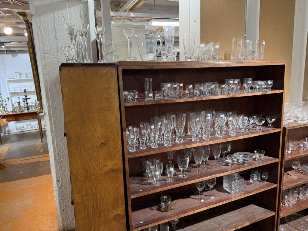 A wooden bookshelf in a Helsinki second-hand shop, packed tightly with various designs of antique Iittala glassware.