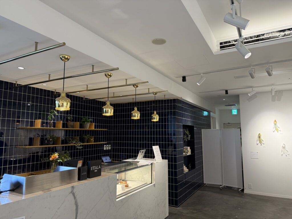 The interior of a cafe with a marble counter, a navy blue tiled wall, and golden pendant lights hanging from the ceiling.