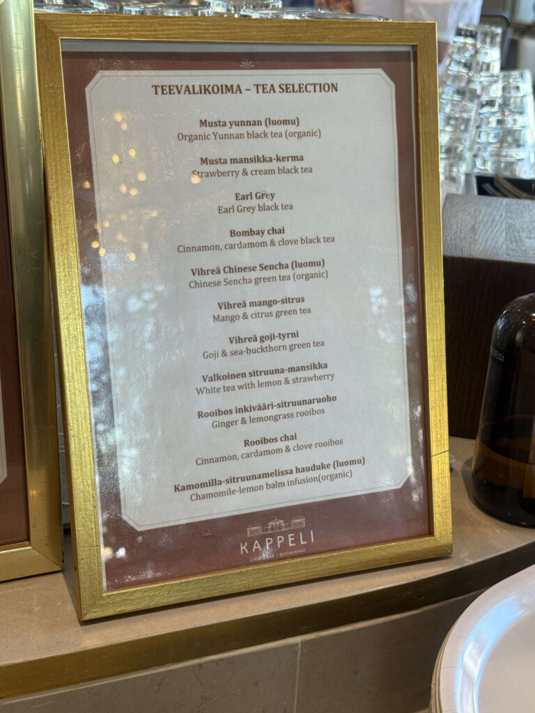 A tea selection menu from the restaurant Kappeli, presented in a gold-colored frame, listing various teas in Finnish and English.