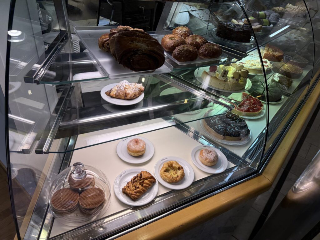 カフェ・アアルトのガラス製ショーケース。クロワッサン、ドーナツ、ケーキ、タルトなど、様々な種類の美味しそうなペストリーが何段にもわたって陳列されている。
