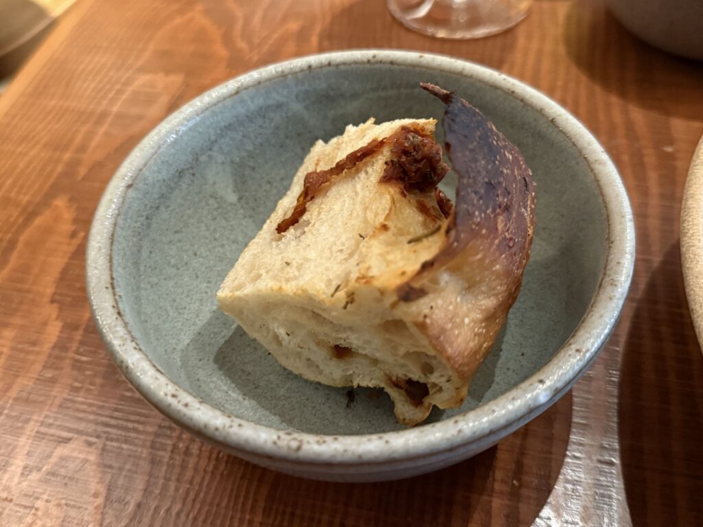 A slice of tomato bread served in a rustic, bluish bowl on a wooden table.