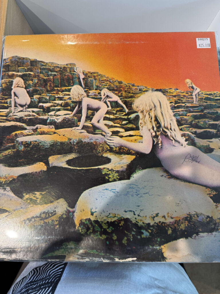The record cover for Led Zeppelin's album 'Houses of the Holy,' featuring naked, blonde children climbing over geometric rock formations resembling the Giant's Causeway under an orange sky.