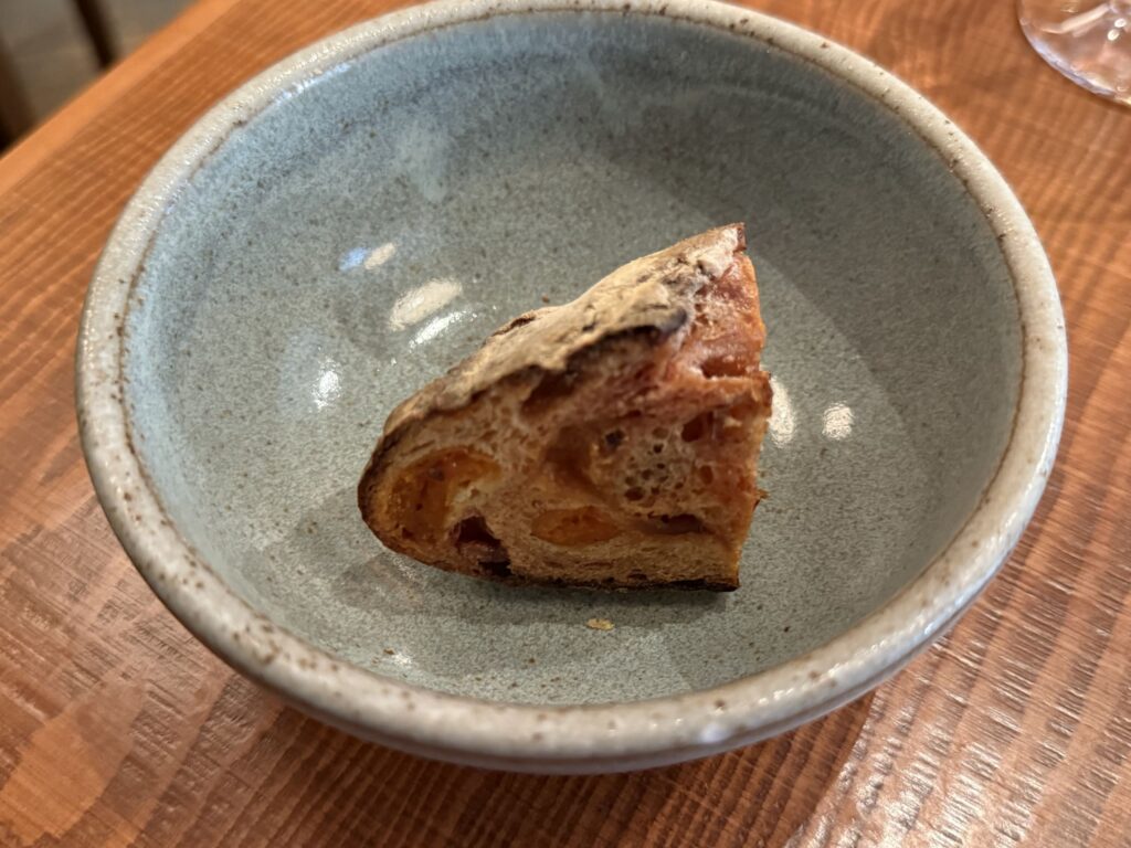 A single piece of beet and apricot bread served in a rustic, light blue ceramic bowl on a wooden table.