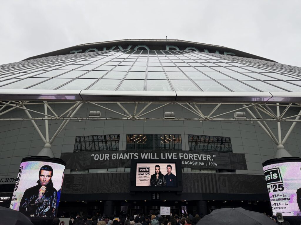 The exterior of the Tokyo Dome under an overcast sky, decorated for an