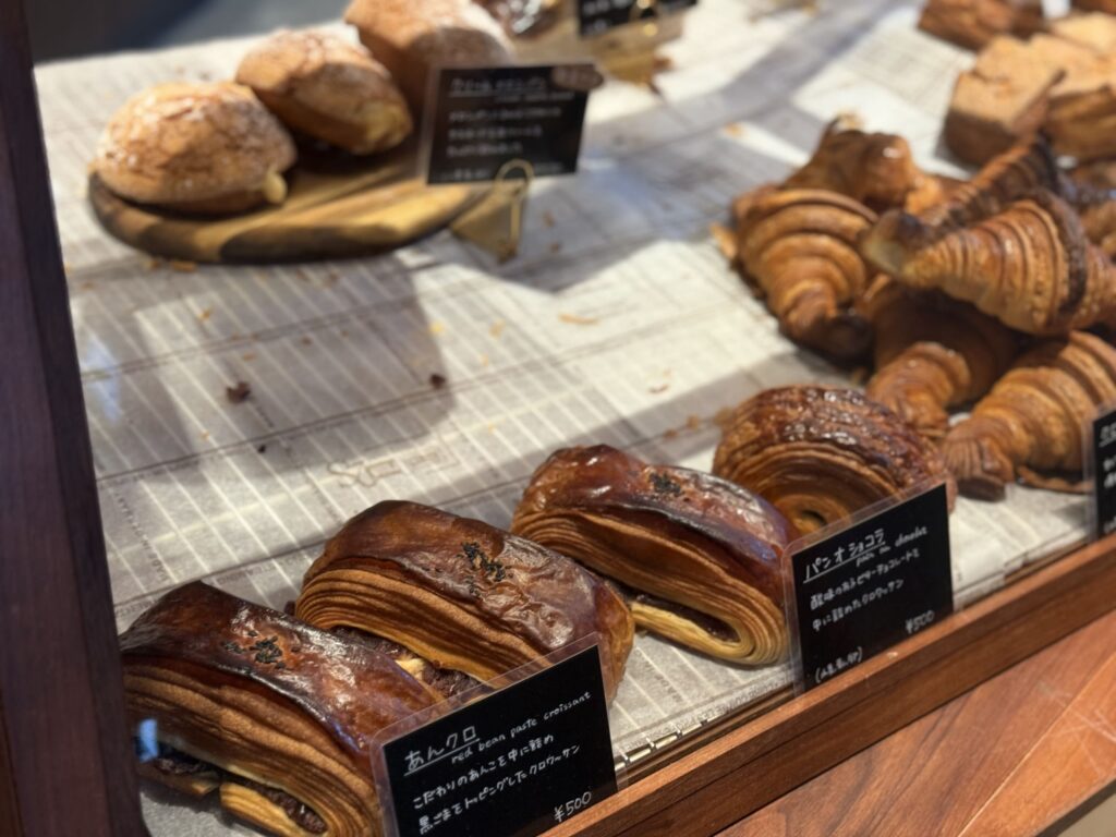 A display case at a bakery filled with freshly baked pastries, including red bean paste croissants, pain au chocolat, and classic croissants.