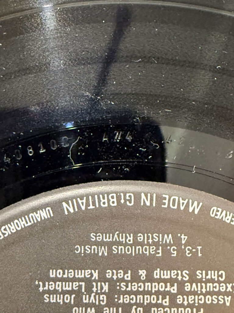 A close-up shot of the run-out groove on a black vinyl record, showing the matrix number 'A4' etched into the dead wax.