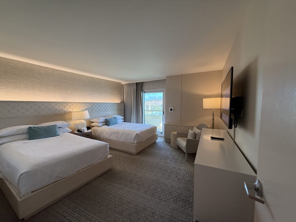 A hotel room with two queen-size beds and a balcony that has a view of Diamond Head.