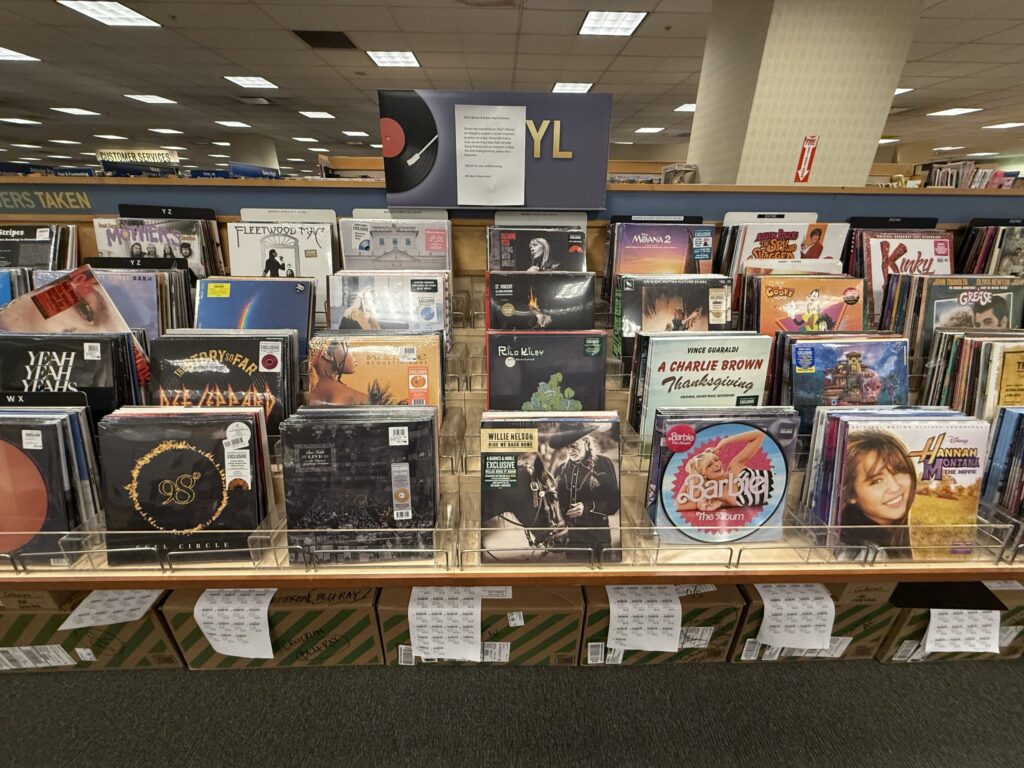 The record section inside a bookstore. Shelves are lined with a wide variety of new vinyl records from various genres.