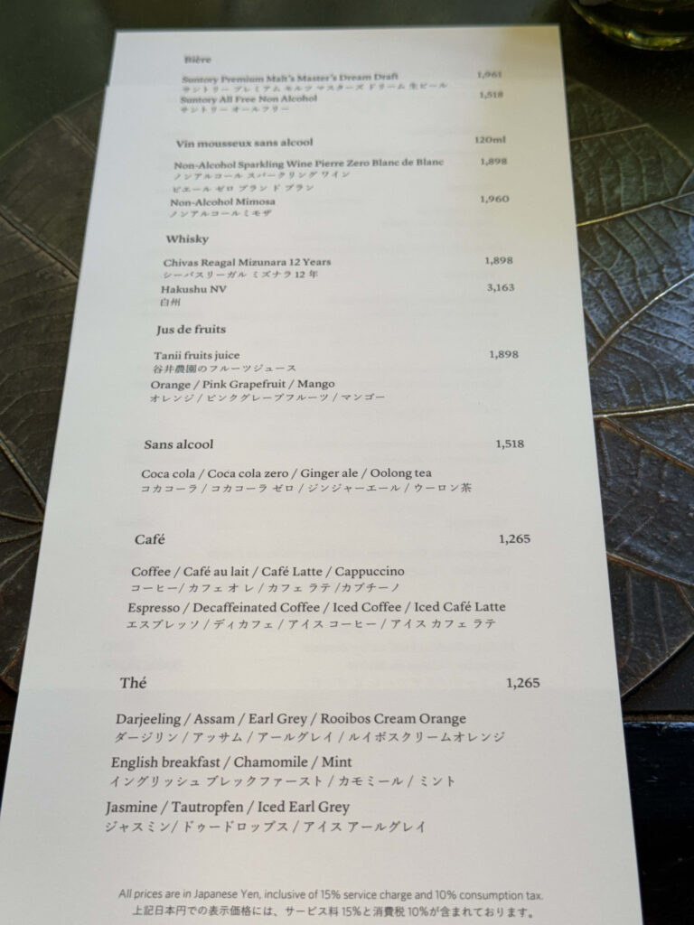 A drink menu written in Japanese and English, placed on a dark table with a leaf pattern.