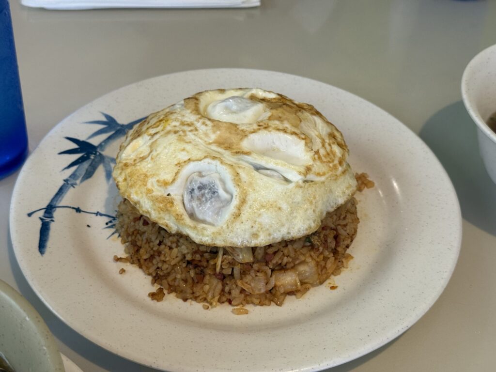 Kimchi fried rice topped with a fried egg, served on a white plate with a blue bamboo pattern.