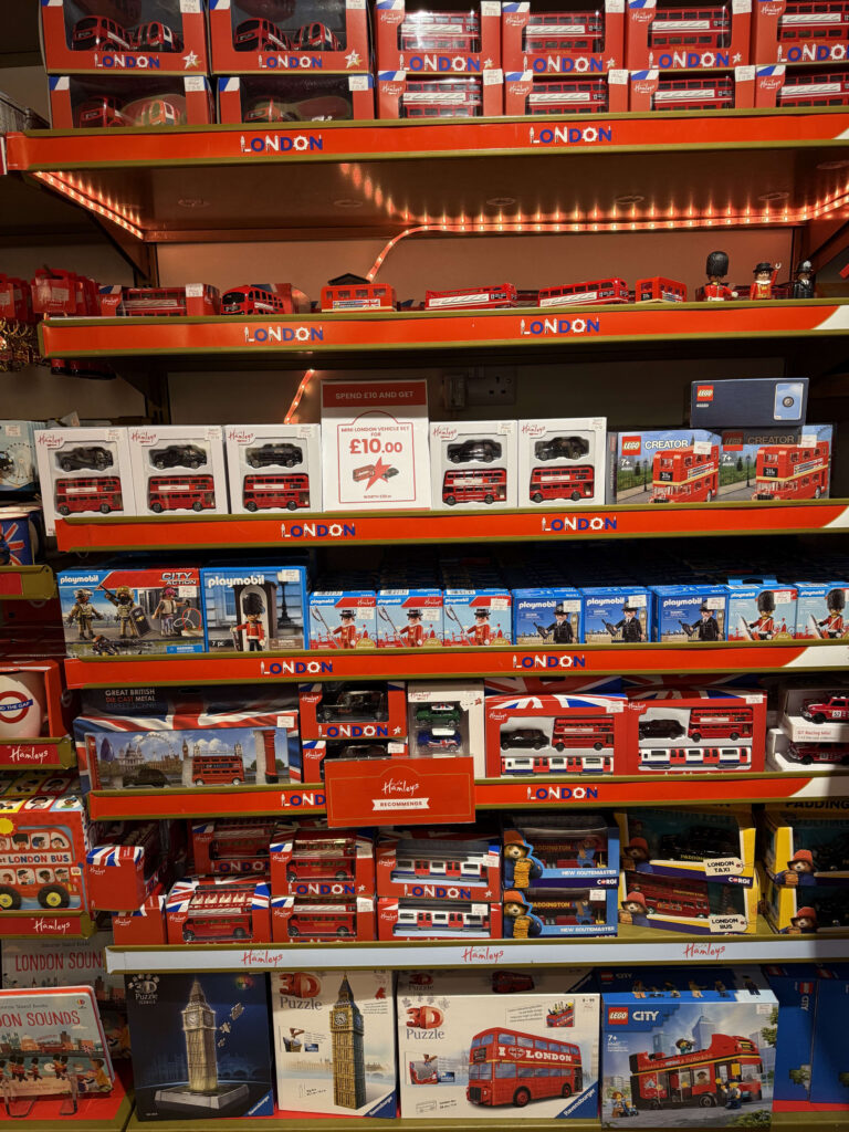 A view of toy store shelves packed with London-themed toys, including red double-decker buses, taxis, and models of Big Ben.