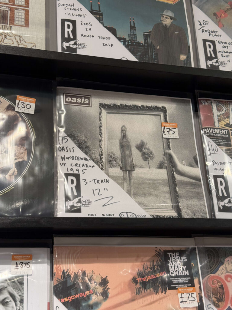 レコード店の棚に陳列されたオアシスの12インチシングル盤「ワンダーウォール」。周りには他のアーティストのレコードも見える。