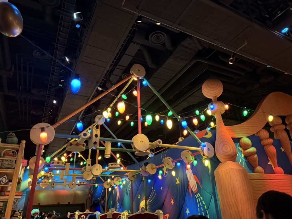 Colorful string lights and giant wooden toy structures hanging from the ceiling inside the Toy Story Mania attraction
