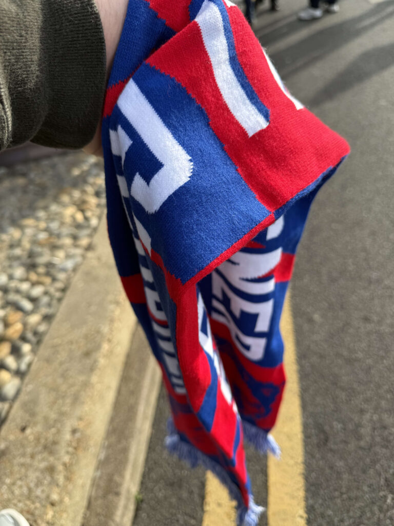 A red, blue, and white knitted scarf held in a hand