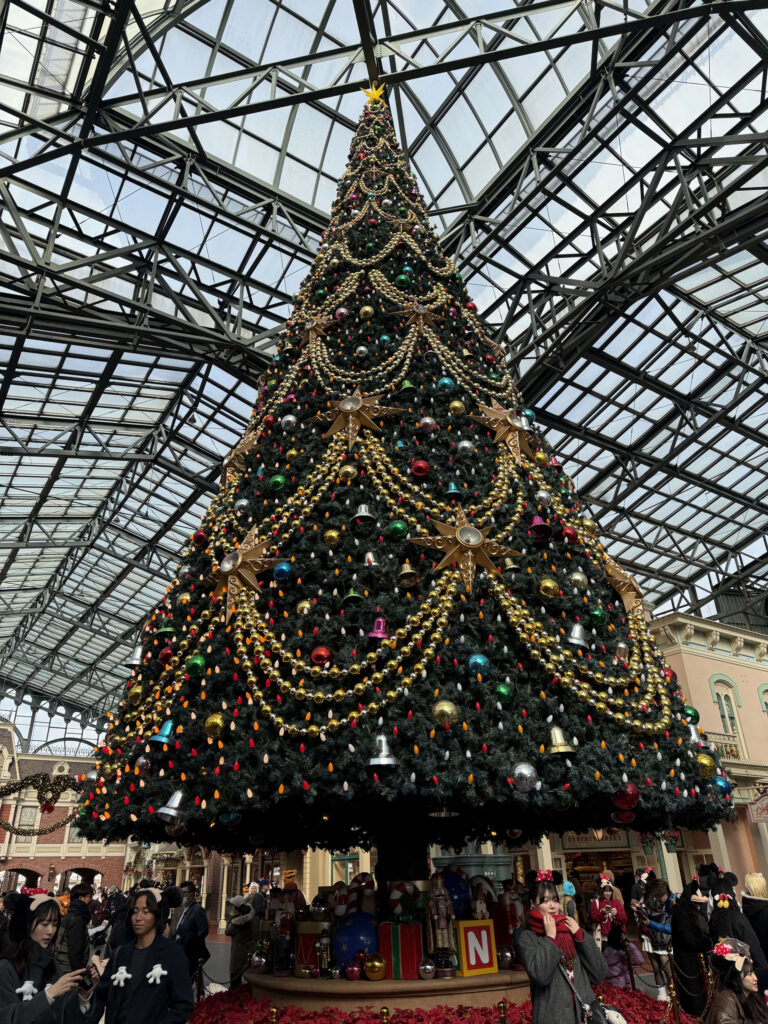A massive, lavishly decorated Christmas tree reaching towards a geometric glass atrium ceiling