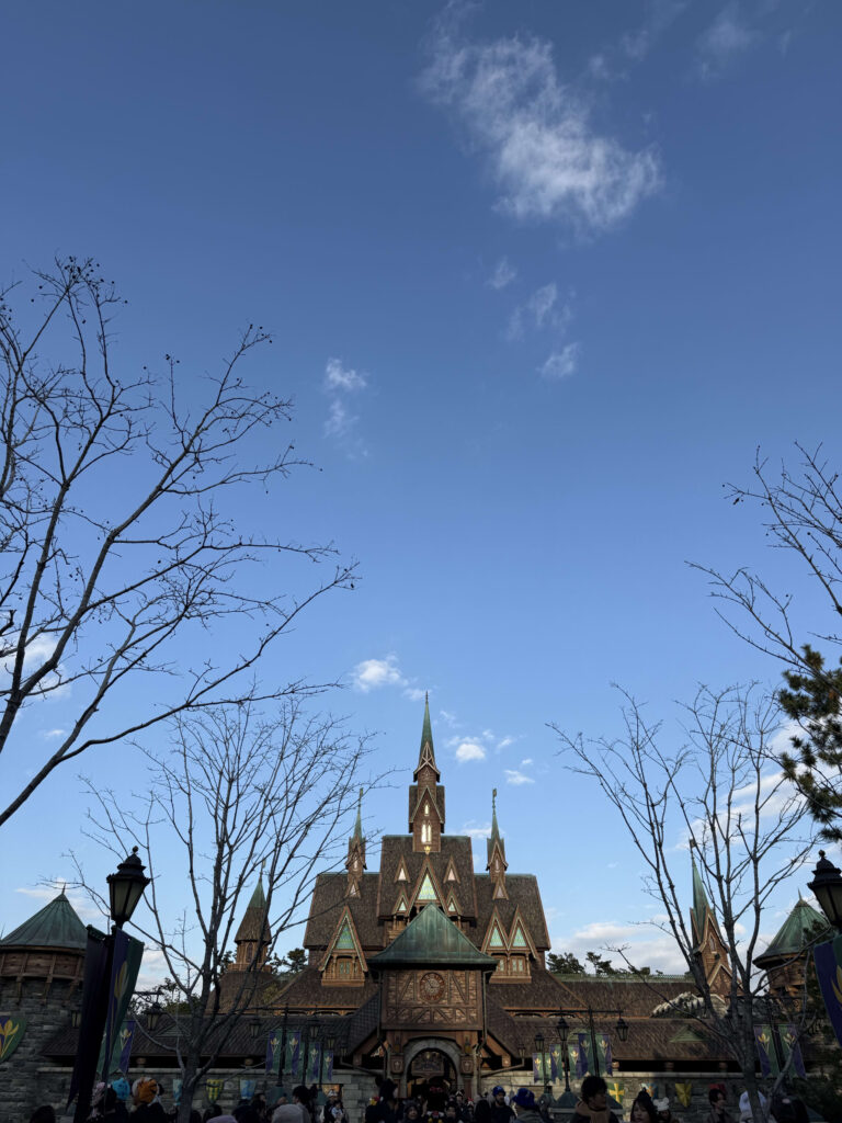 青空を背景に、冬の木々の枝の間から姿を現したアレンデール城