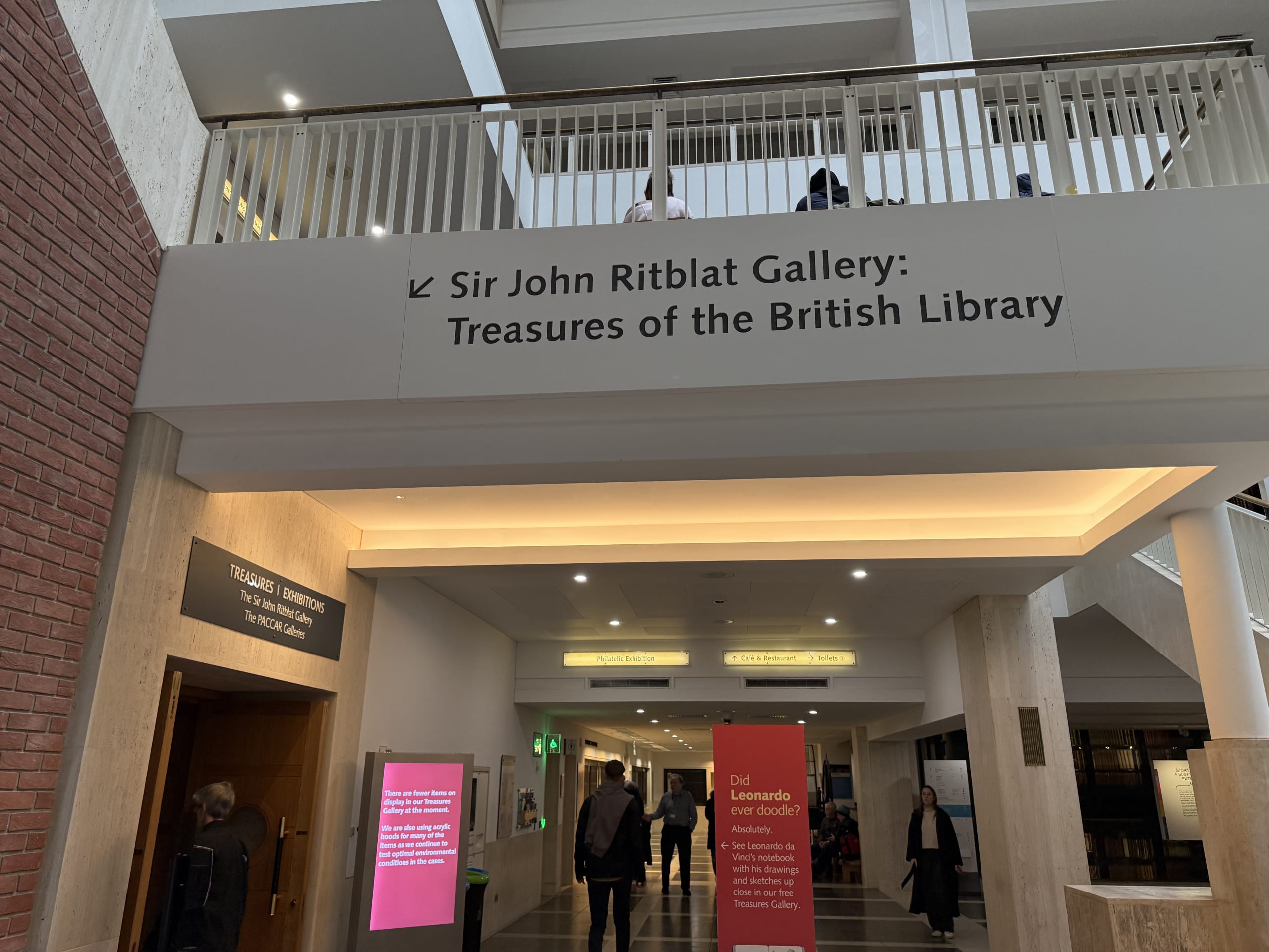 Signage for the Sir John Ritblat Gallery: Treasures of the British Library hanging above a hallway entrance inside the library