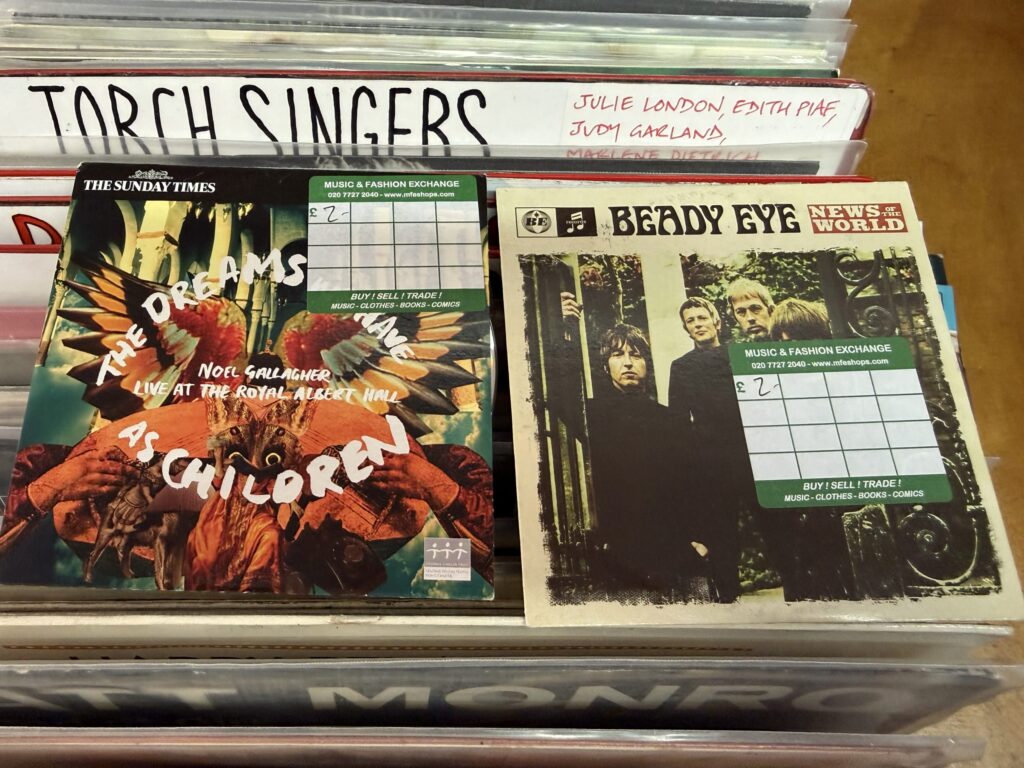 Copies of Noel Gallagher's 'The Dreams We Have as Children' and a Beady Eye CD sitting in a record store bin with price stickers