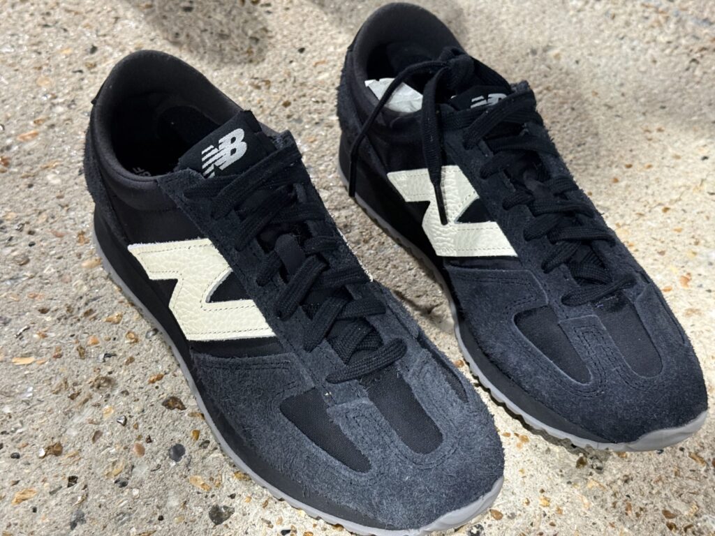 コンクリートの地面に置かれたNew Balance 471 × JUNYA WATANABE MANの黒いスニーカー