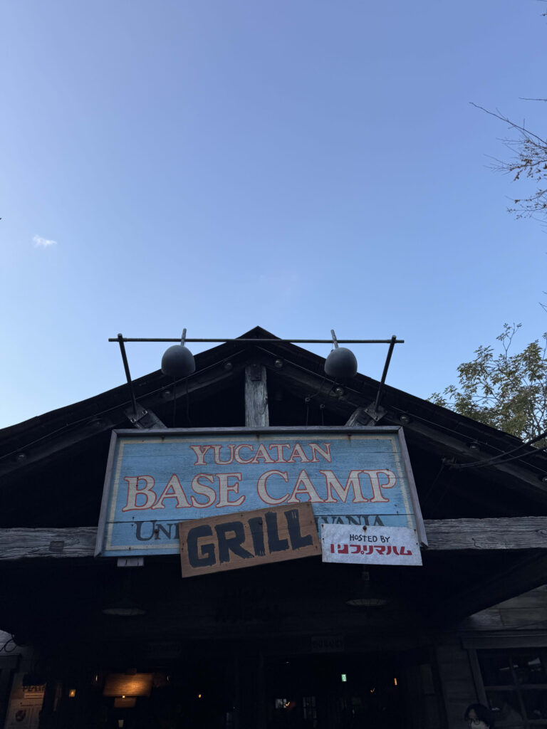 Wooden signboard for the Yucatan Base Camp Grill restaurant at Tokyo DisneySea against a clear blue sky