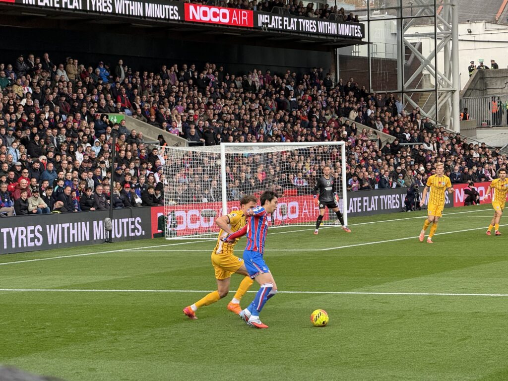 Daichi Kamada of Crystal Palace dribbling the ball in a packed stadium