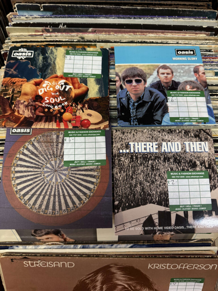 レコード店の棚に並ぶオアシスの「Dig Out Your Soul」「Morning Glory」などのシングルやソングブック