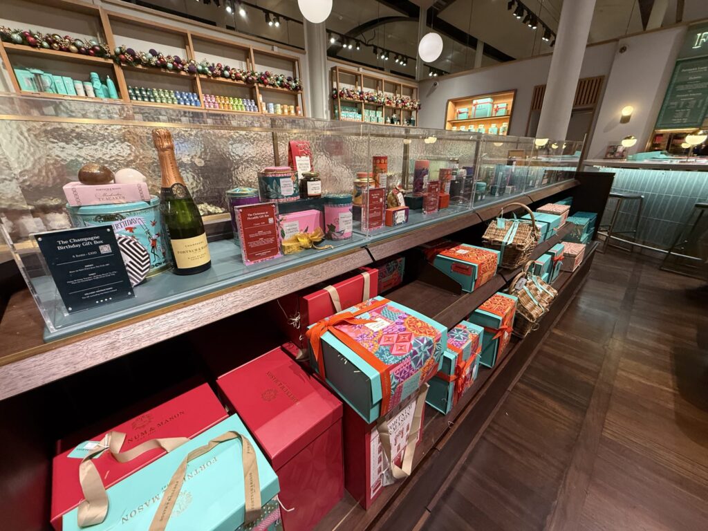 フォートナム・アンド・メイソンの店内ディスプレイ。シャンパン、紅茶の缶、色とりどりのギフトボックスが並ぶ棚