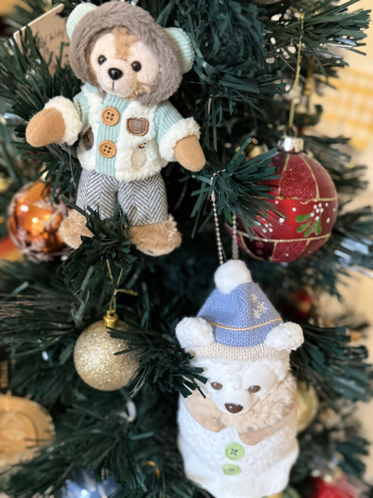 クリスマスツリーに飾られたダッフルコートを着た茶色のクマと、青いニット帽を被った白い雪だるま風のクマのぬいぐるみオーナメント