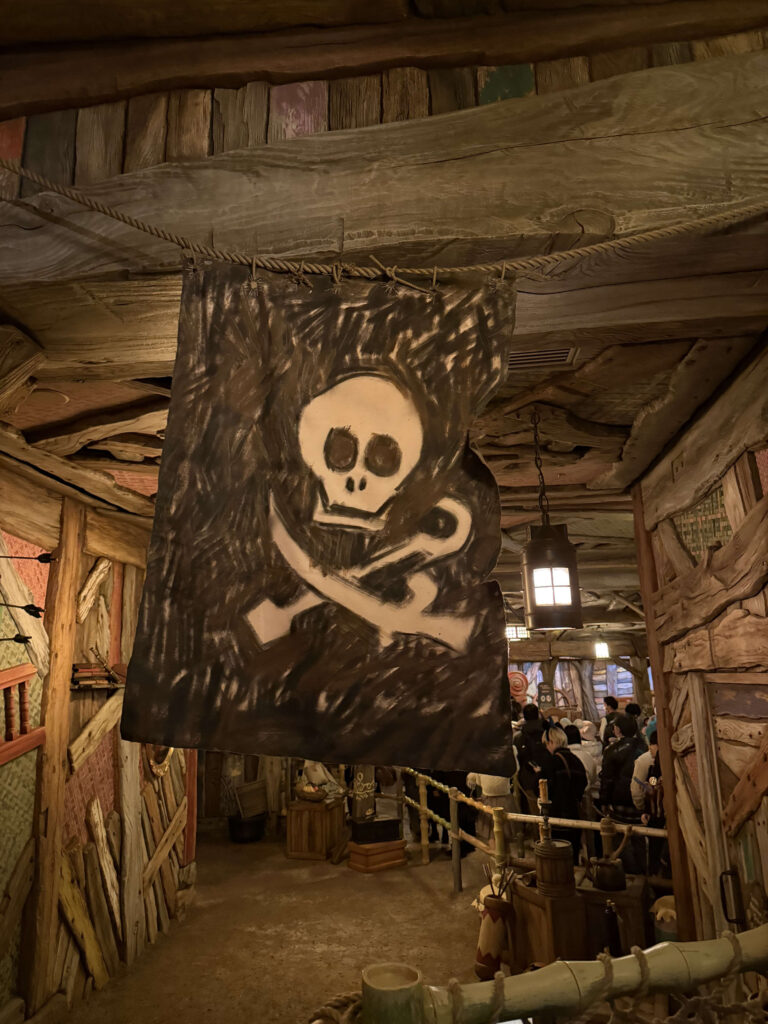 A hand-painted Jolly Roger flag hanging from a rope inside a rustic wooden interior themed after Peter Pan.