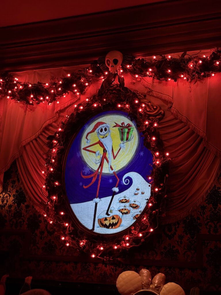 Portrait of Jack Skellington dressed as Sandy Claws surrounded by red lights and garlands at the Haunted Mansion
