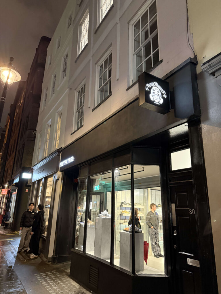 Nighttime exterior of the Foot Patrol sneaker store on Berwick Street, London, featuring the illuminated gas mask logo.