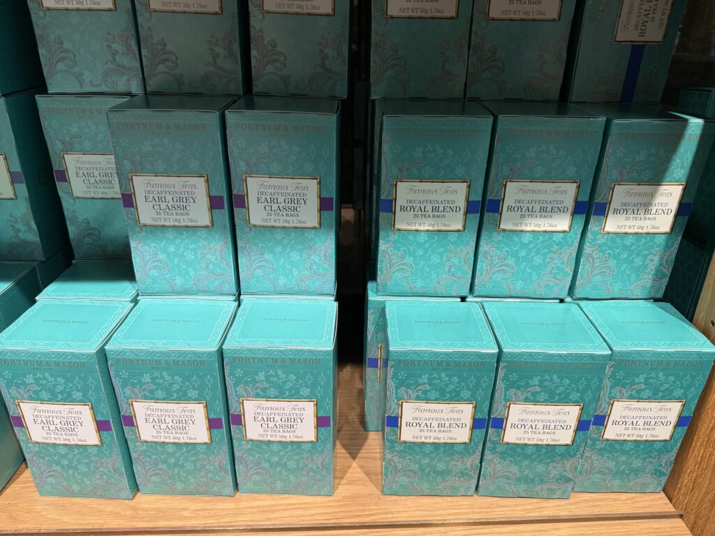 Stacks of Fortnum & Mason Decaffeinated Earl Grey Classic and Royal Blend tea boxes on a wooden shelf