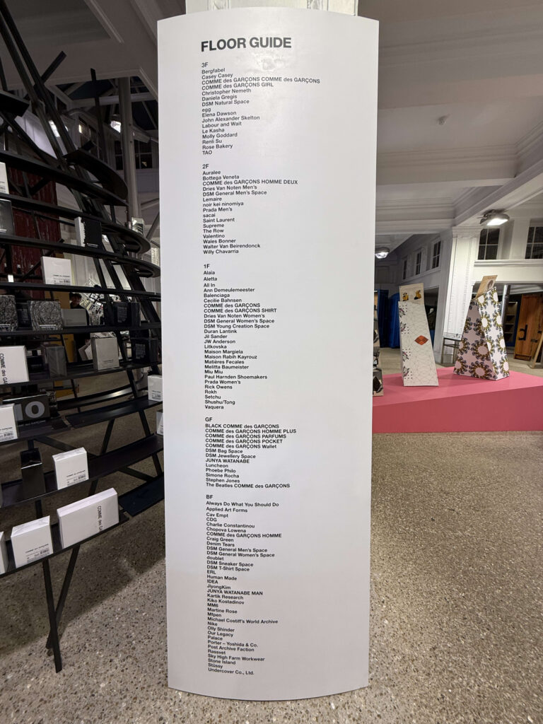 Tall white floor guide signage at Dover Street Market London listing brands by floor from BF to 3F.