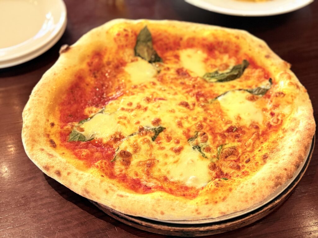 Margherita pizza with tomato sauce, melted cheese, and basil on a wooden table