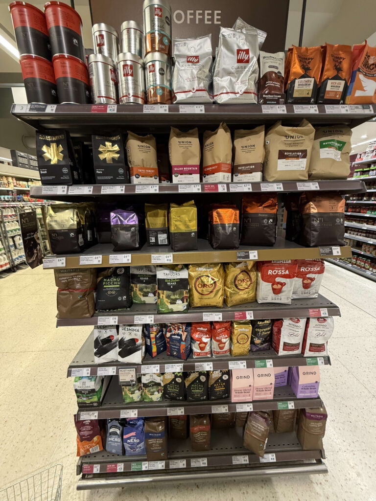 Various brands of coffee beans and ground coffee displayed on supermarket shelves