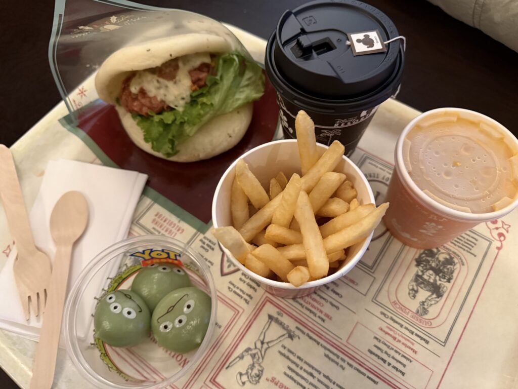 東京ディズニーリゾートの食事トレイ。チキンパオサンドイッチ、フライドポテト、リトル・グリーン・まん、コーヒー、スープが並んでいる。
