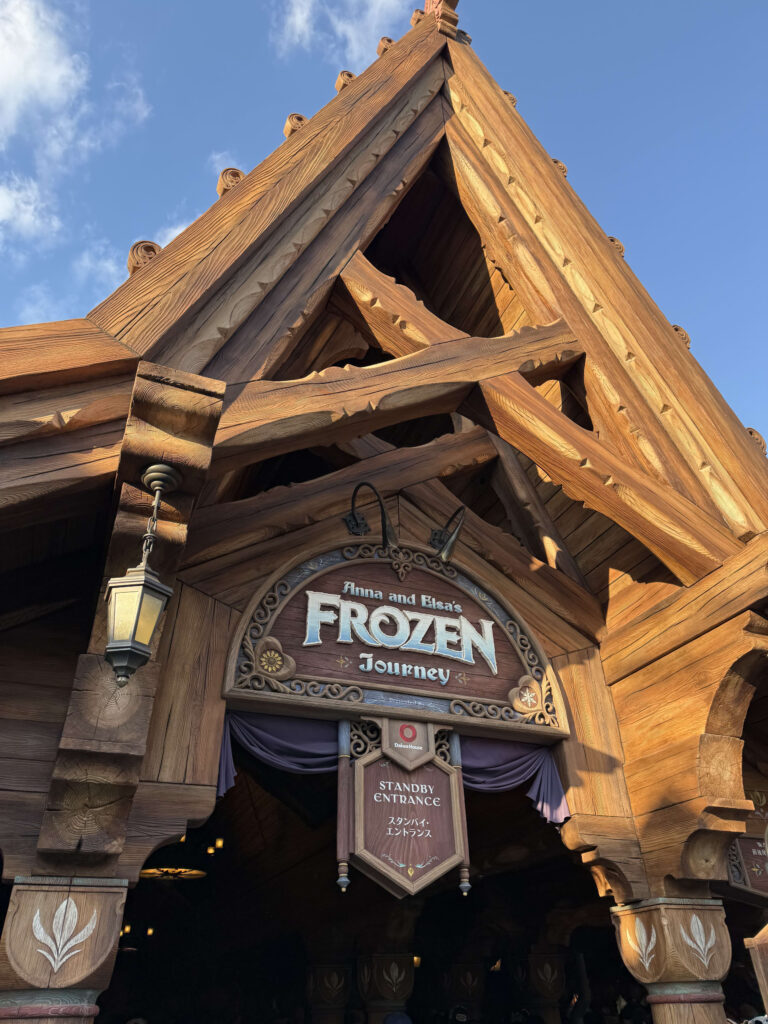 Wooden entrance and sign for Anna and Elsa's Frozen Journey attraction against a blue sky